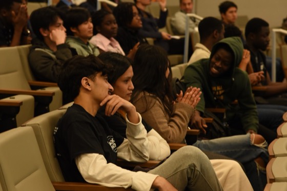 Hackers seated in the auditorium, one clapping