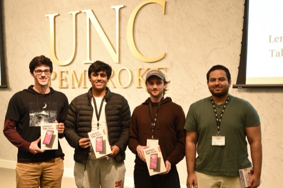 Four winners holding Lenovo tablets on stage