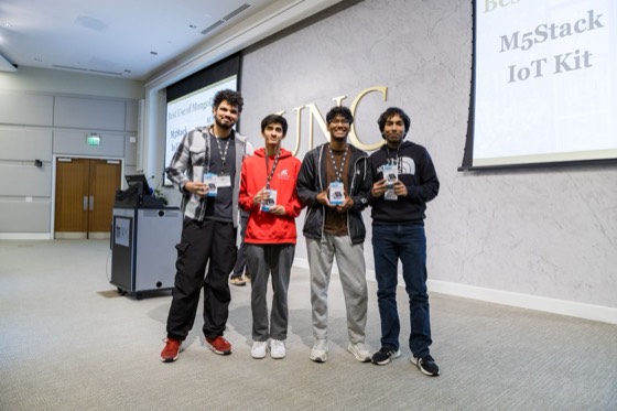 Four winners holding M5Stack IoT kits on stage