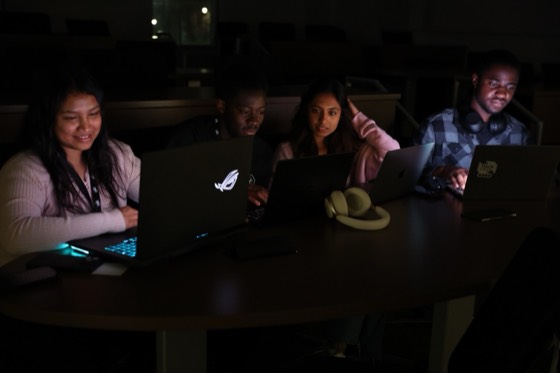 Four teammates working together at a table in the dark